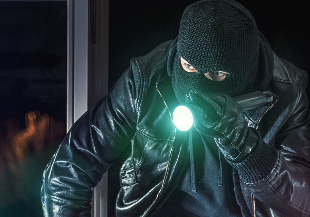 Einbrecher mit Sturmhaube und Taschenlampe